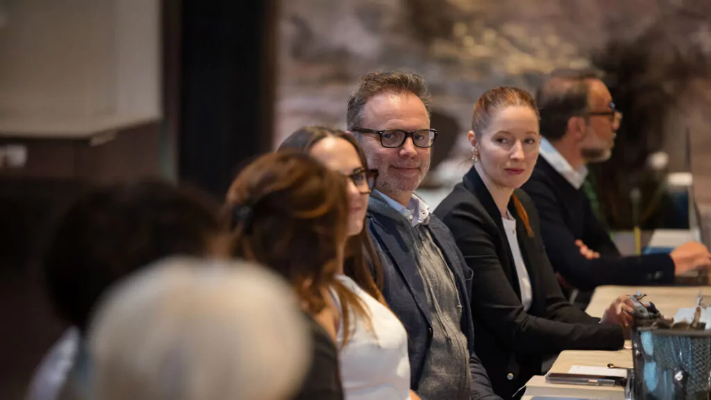 a row of people sitting at a table in a conference room